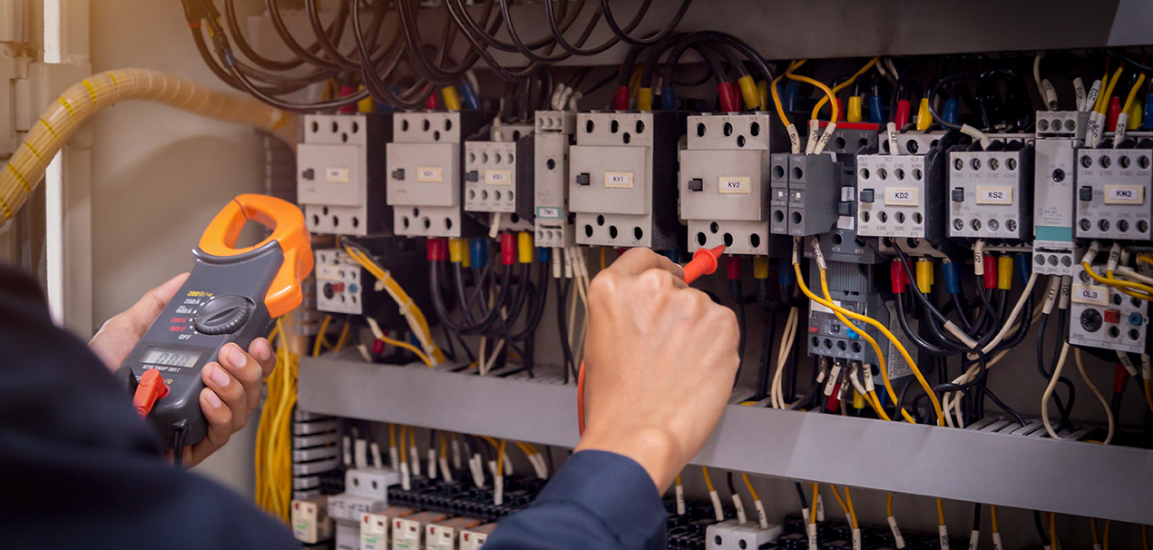 Electrical technician diagnosing an industrial control panel