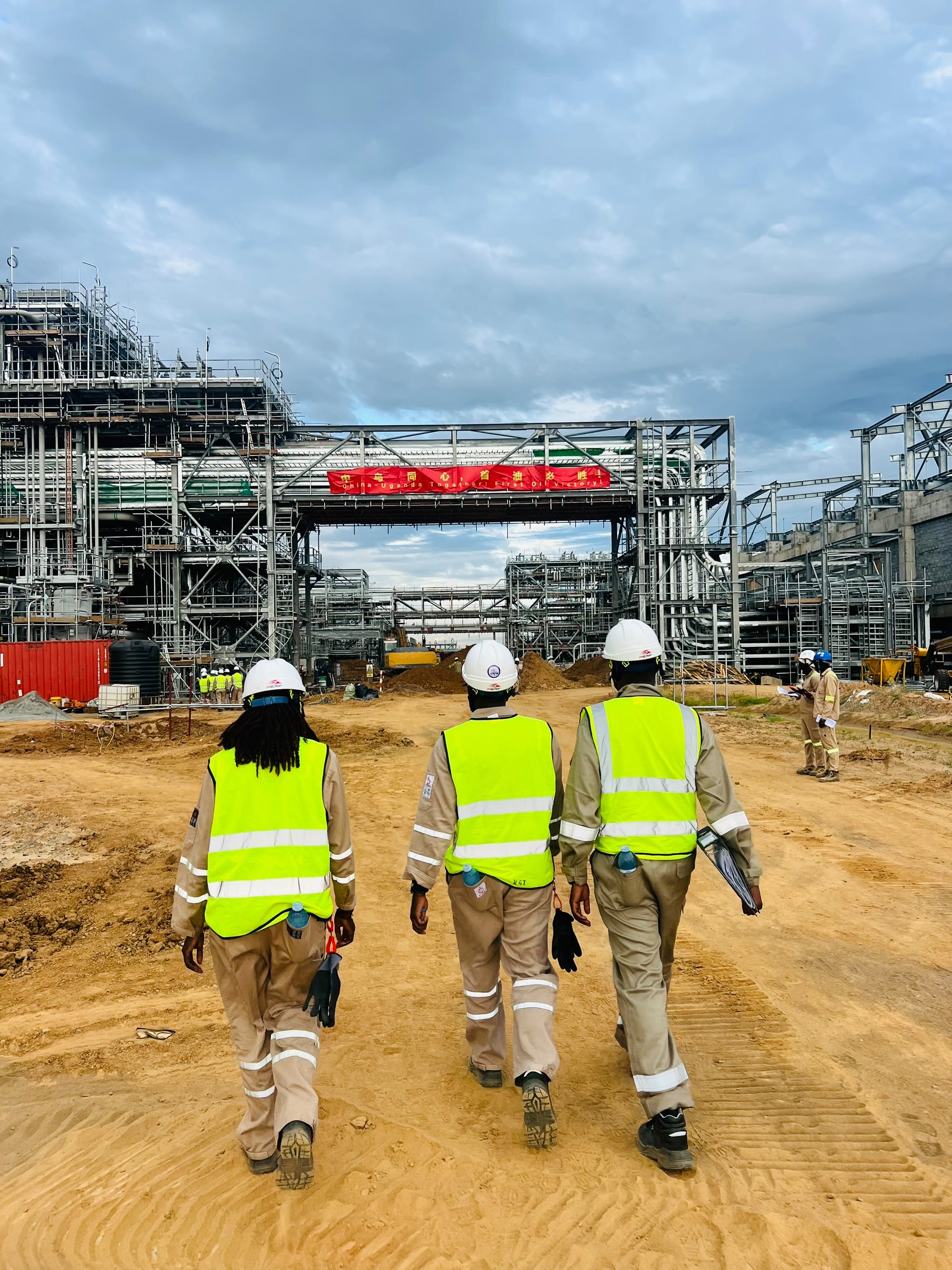 Technical field team in reflective safety jackets approaching an industrial installation